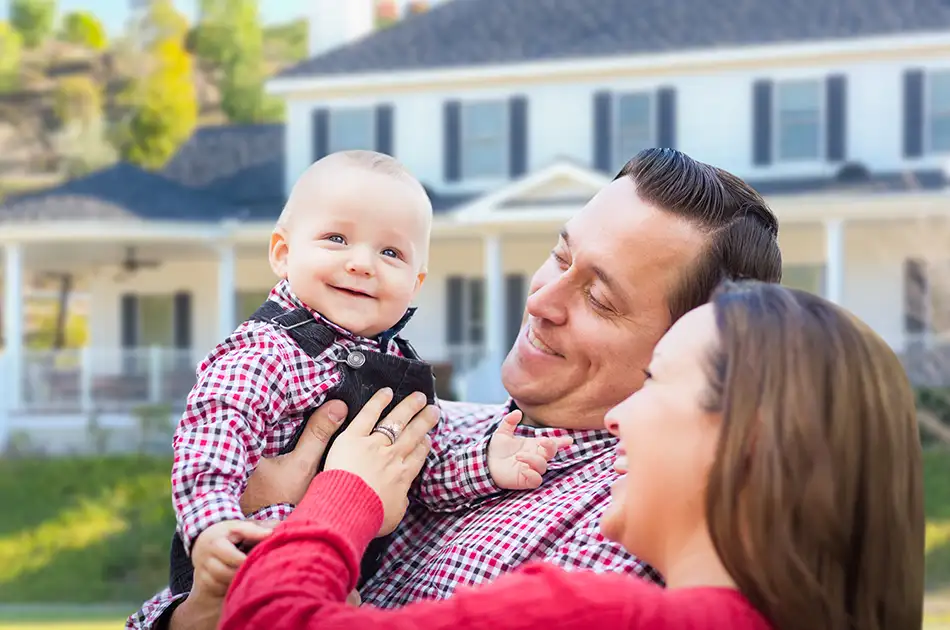 young family with smiling baby outside of home