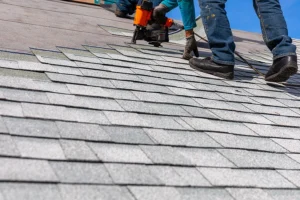 Roofers using a nail gun to install new shingles on a roof in Central, IL.