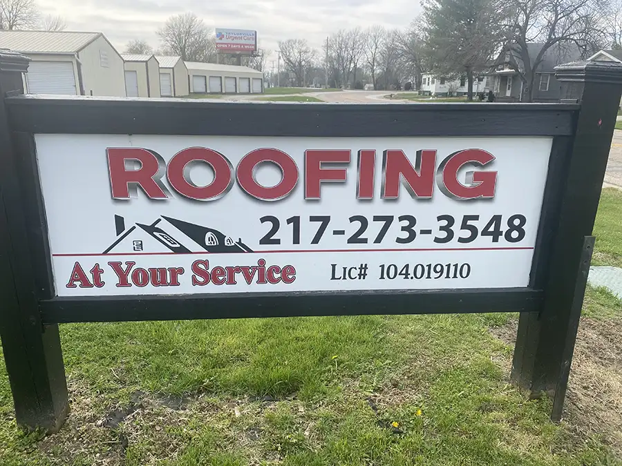 An outdoor sign advertising for At Your Service Roofing in Pana, IL