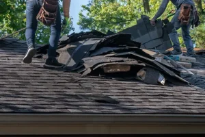 At Your Service Roofing crew removing damaged shingles from a home in Taylorville, IL, as they prepare for a full roof replacement.