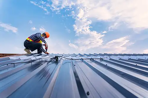 At Your Service Roofing—A professional roofer installs a new metal roof on a commercial building in Taylorville, IL.