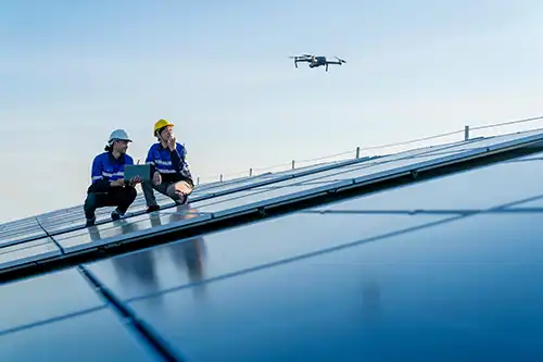At Your Service Roofing—Two roofing technicians are on the roof of a building in Springfield, IL, using a remote to control a drone.