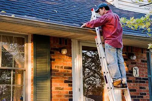 At Your Service Roofing—A man inspects his roof and the gutters outside his home in Shelbyville, IL as ways to help improve the lifespan of his roof.