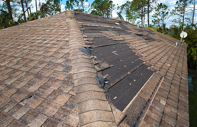 Damaged house roof with missing shingles after wind storm central illinois
