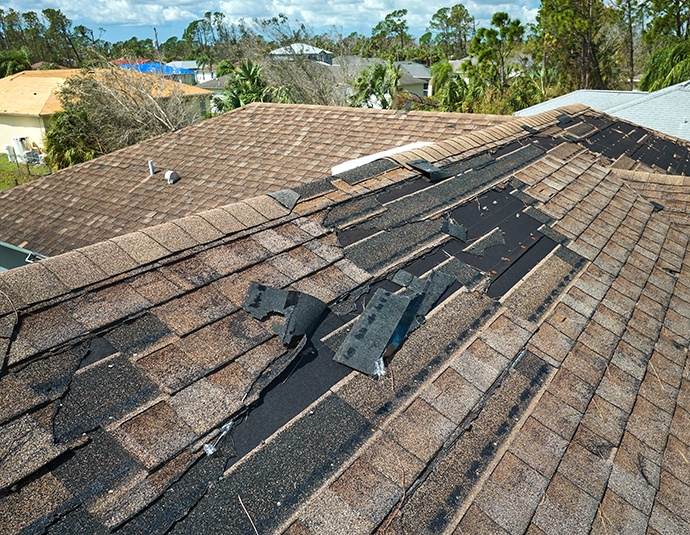 Wind damaged house roof with missing asphalt shingles after wind storm central illinois